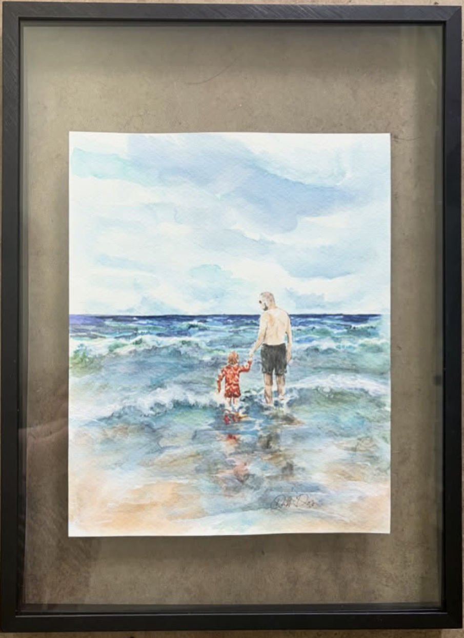 Framed watercolor painting of an adult and child wading together in the ocean surf